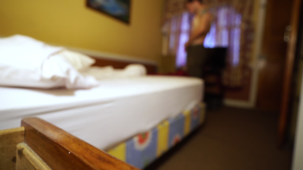 joven atlético viajero caucásico preparándose por la mañana para viajar de mochilero en una habitación de albergue