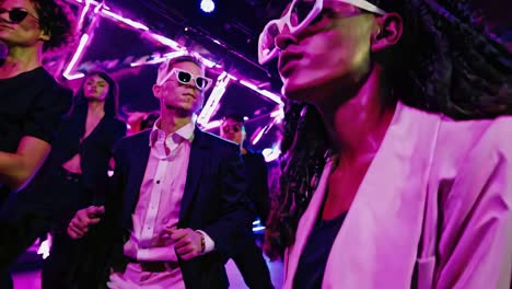 stylish people dancing in a night club with neon lights