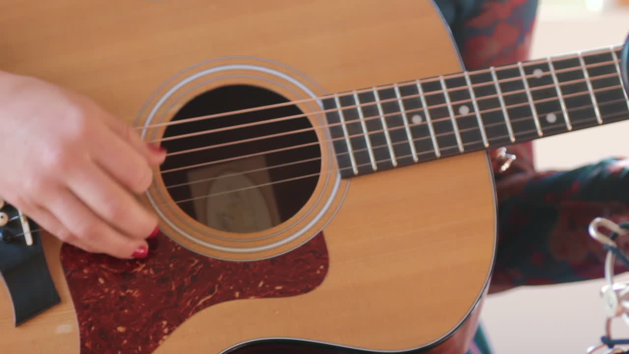 Young woman playing guitar and singing into microphone