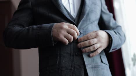 abotonamiento de la chaqueta manos cerca. hombre en traje fija los botones de su chaqueta preparándose para salir