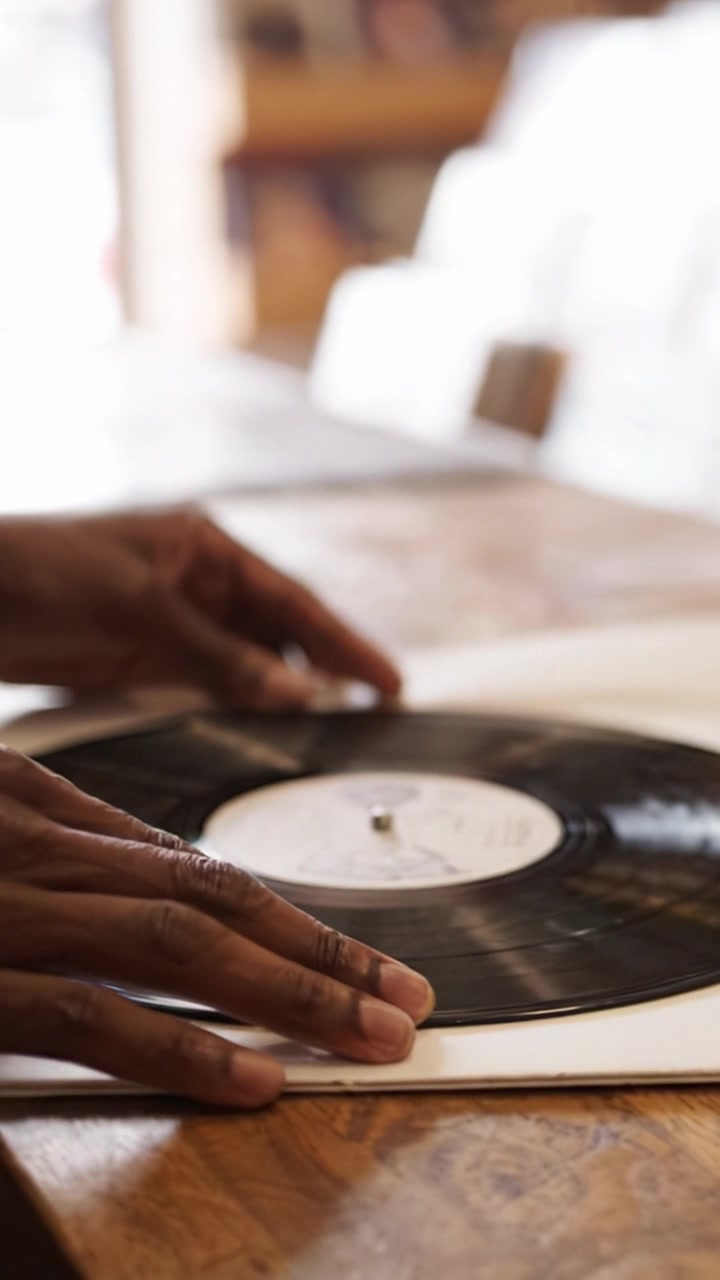 Una Persona che Maneggia Delicatamente un Disco in Vinile su un Tavolo di Legno, Catturando le Complessità del Collezionismo Musicale e la Gioia dell'Esplorazione dei Dischi