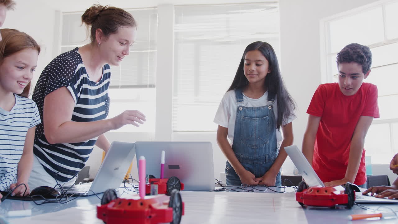estudiantes emocionados viendo el vehículo robot moverse después de la lección de codificación en la clase de programación de computadoras