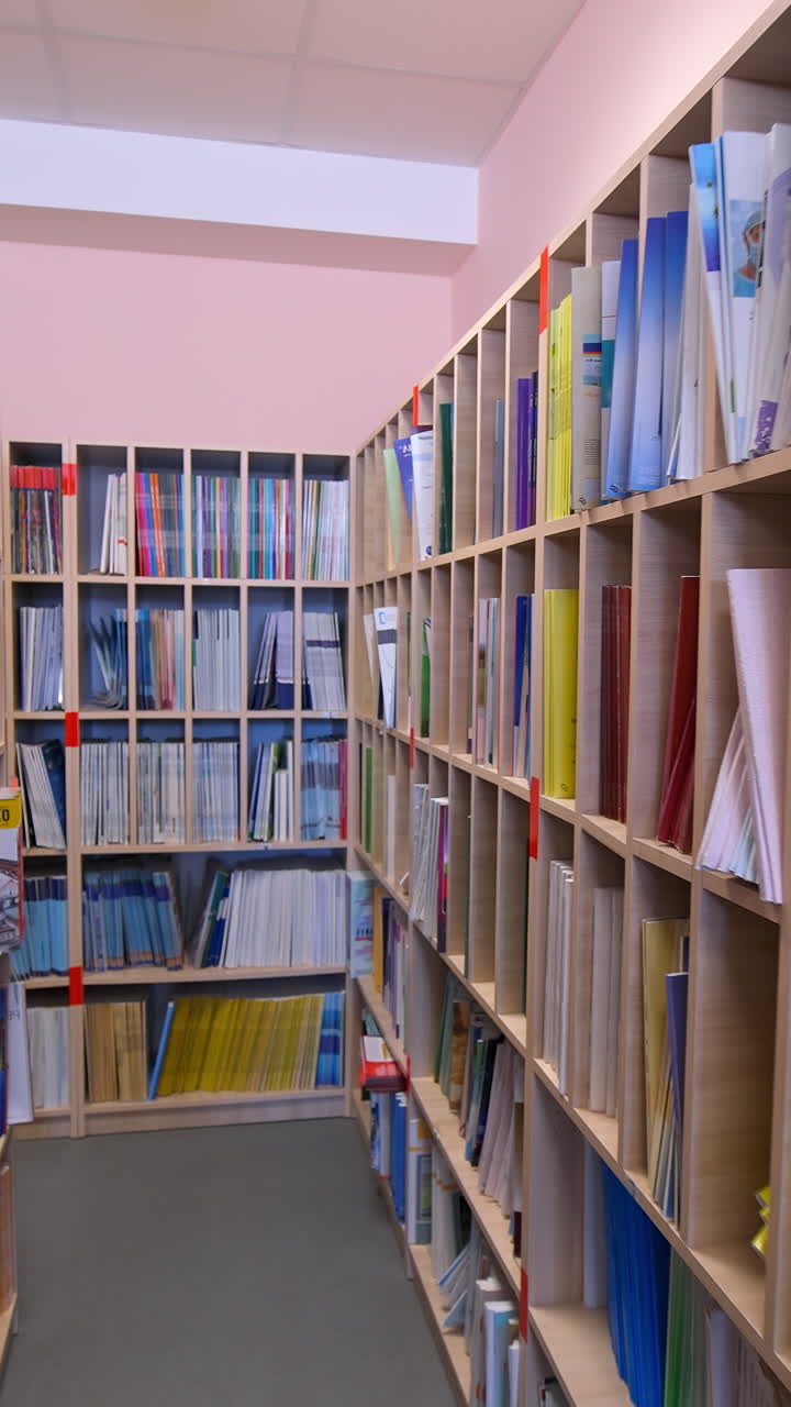 Bookshelves in university library. Interior of the library with shelves full of books. Vertical video
