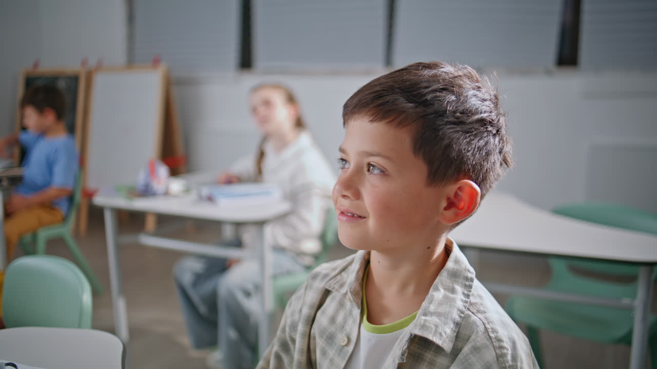 Primo piano di un bambino allegro che studia. Bambino felice e sorridente che ascolta l'insegnante