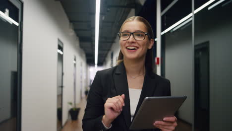 mujer de negocios sonriente tocando la tableta caminando por el pasillo de la oficina. especialista ceo feliz