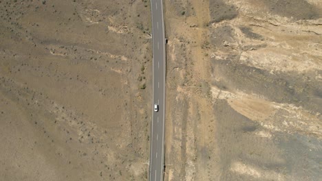 Top-Down-Aerial-View,-Cars-Moving-on-Desert-Road-Between-Volcanic-Hills-in-Rural-Lanzarote,-Canary-Islands-Spain