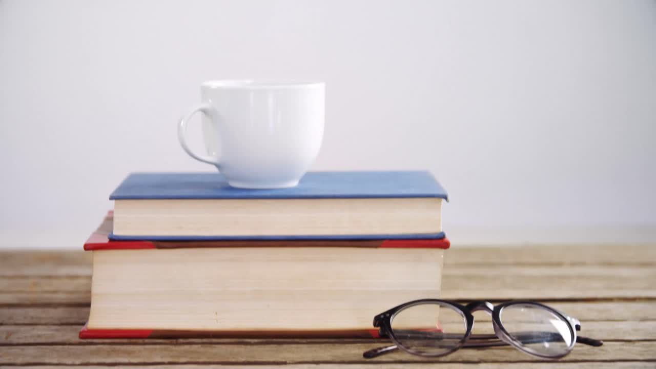 Books, coffee cup and spectacles on wooden table 4k