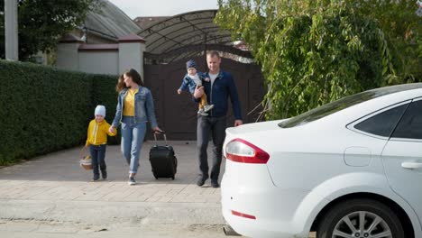 family trip, caring parents with male children put things in trunk of car during trip to countryside