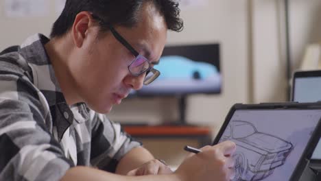 close up of asian male yawning while drawing new car design concept on a tablet in the studio with tv and computers display 3d electric car model