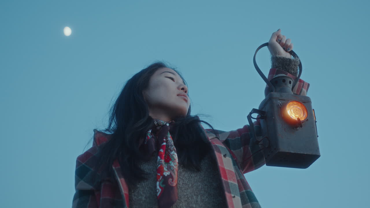 저녁 에 푸른 하늘 아래 신호 등불 을 들고 있는 젊은 아시아인 여자