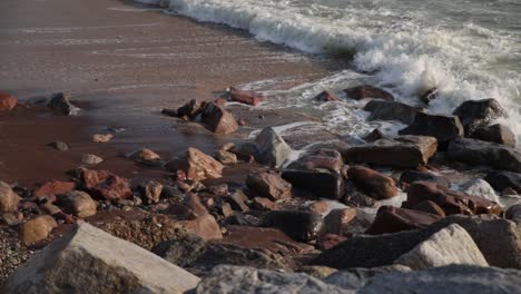 waves crashing on multicolored rocks and red sand on a beach in swakopmund, namibia