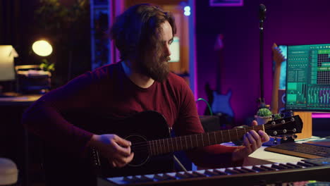 portrait of male songwriter playing acoustic guitar and recording musical sounds