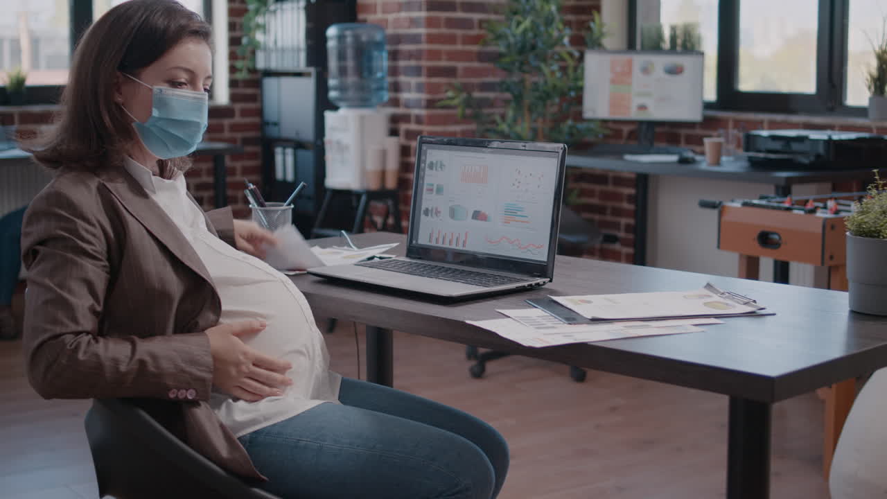 Pregnant woman with face mask working on development