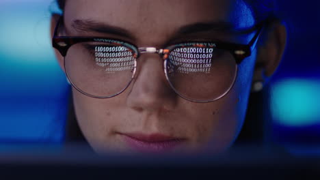 close up portrait young woman programmer using computer browsing code data looking at binary information on screen wearing glasses