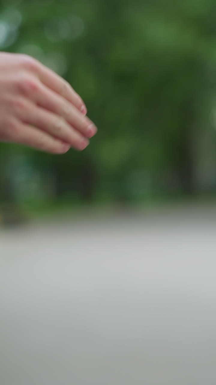 primer plano de dos manos interactuando lúdicamente con un golpe de nudillo, una mano, en una manga gris, se extiende hacia la otra, contra un fondo de parque borroso con vegetación y edificios