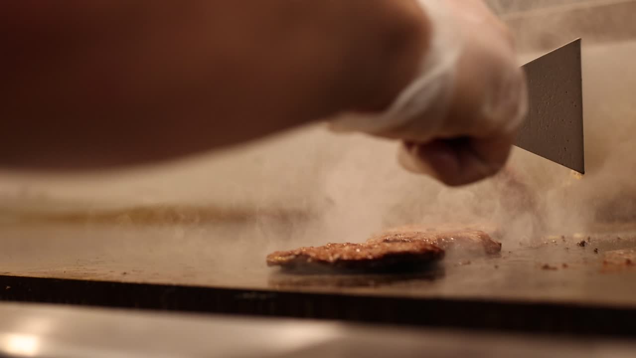 손으로 버거 고기 패티를 뒤집는 것