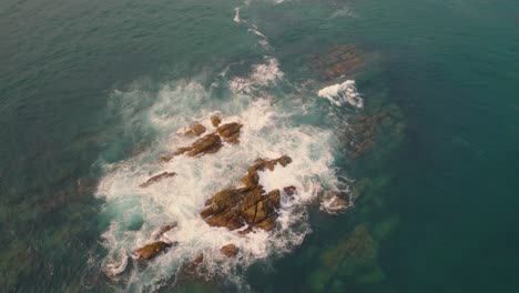 Aerial-Circle-Dolly-Around-Rocky-Outcrop-With-Ocean-Waves-Breaking