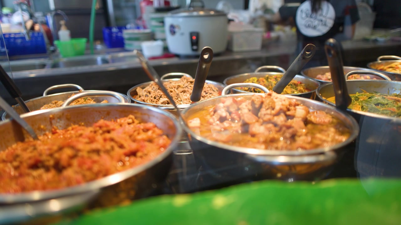 Primo piano di vari piatti di street food thailandese in vassoi di metallo in un ristorante di Bangkok.