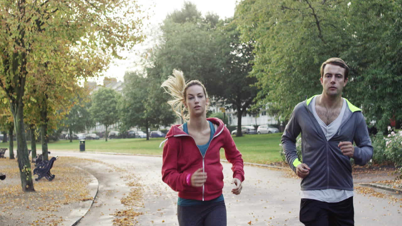 Athletic couple running in park wearing wearable technology connected devices