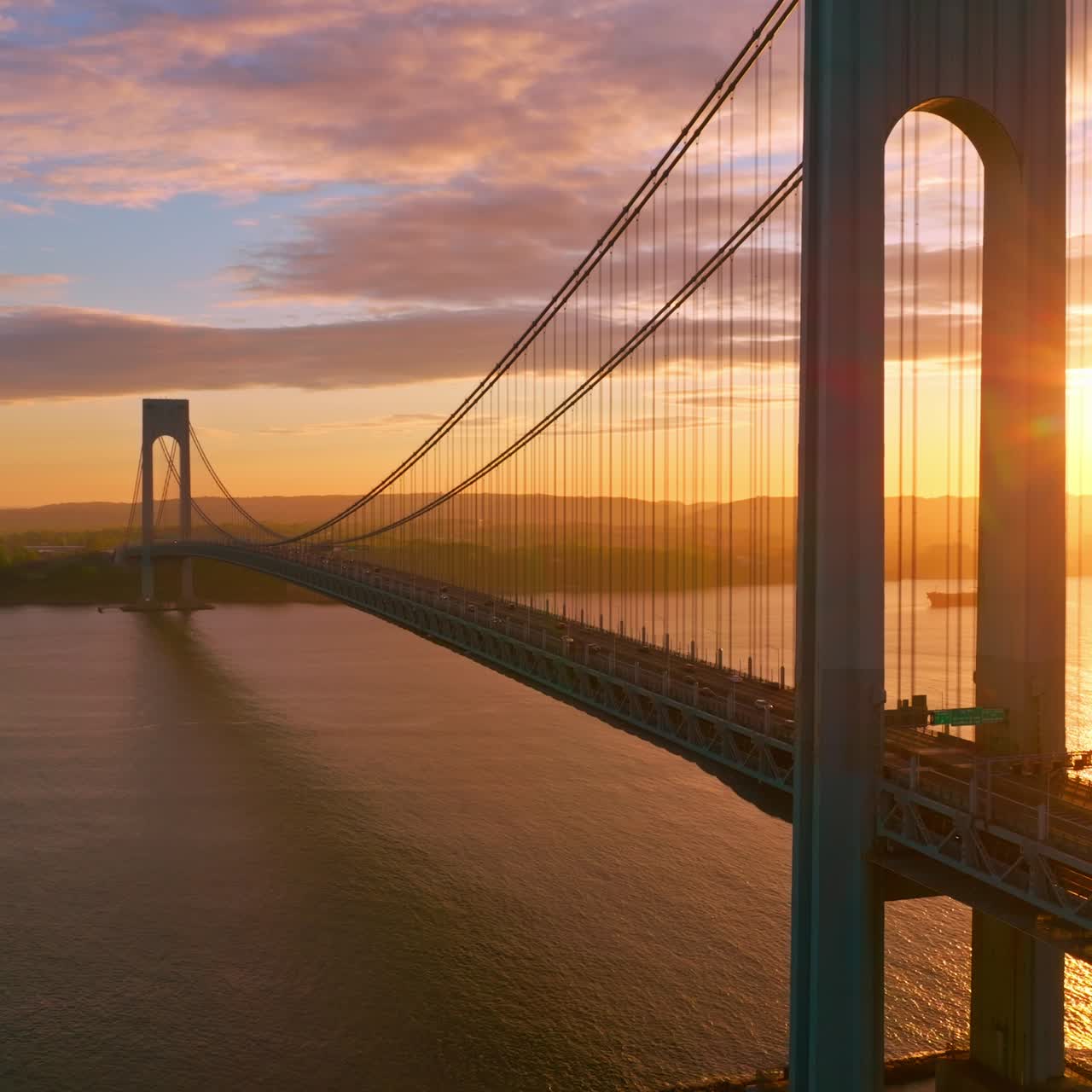 Calm waters of East River at setting sun. Beautiful construction of Whitestone bridge with quick traffic