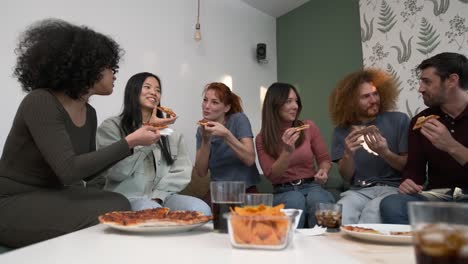Diverse friends cheering up for woman bringing pizzas during weekend party at home