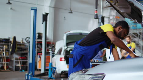 el ingeniero reemplaza el motor del coche en el garaje
