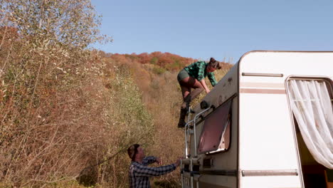 beautiful caucasian young woman getting down from the top of her camper van