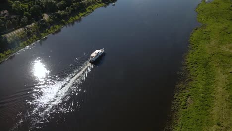 aerial shot of a ferry boat sailing on river nemunas with beautiful nature near kaunas, lithuania