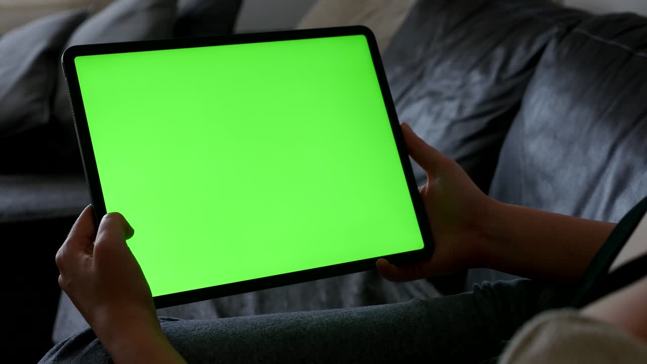 Female stays at home and looks to green screen tablet display 4K video