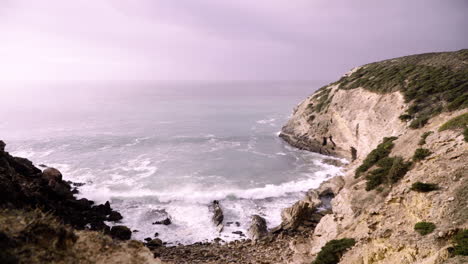 big waves roll into a rocky beach in the algarve portugal