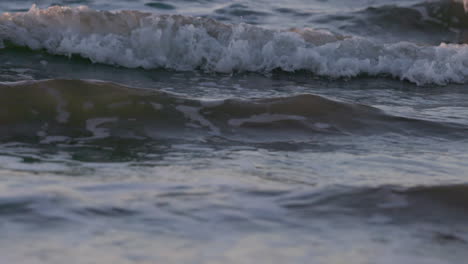 olas del mar corriendo en la playa durante la puesta de sol