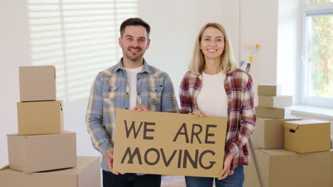 couple holding sign that says "we are moving"