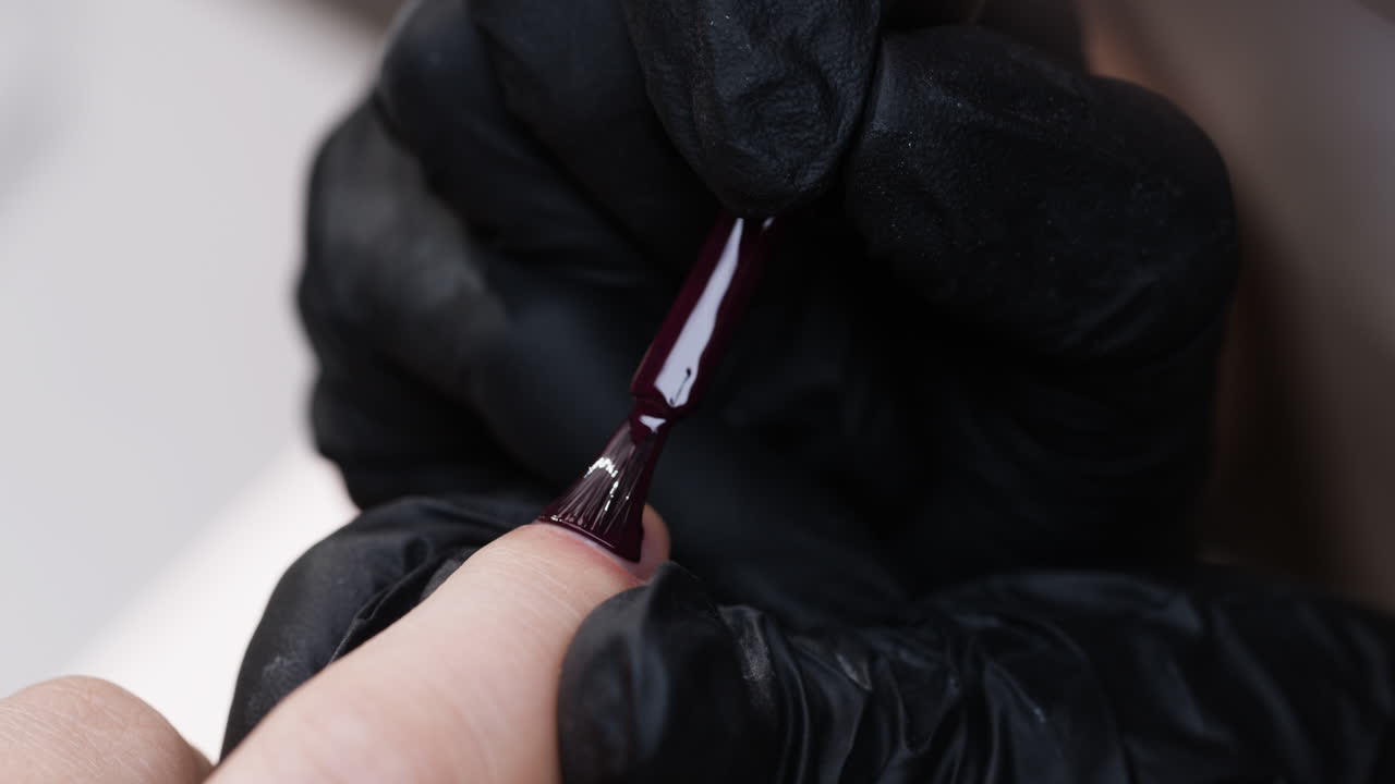 aplicación de esmalte de uñas rojo oscuro