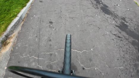 pov of bicycle bike wheel moving and tunring whilst rolling along tarmac with cracks. healthy exercise fitness footage.