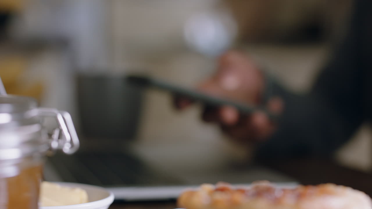 close up hands using smartphone browsing online working in kitchen eating waffles enjoying relaxing morning at home