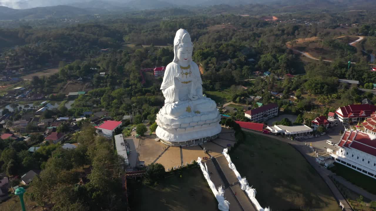 drone aéreo de wat huay pla kang gigante blanca gran estatua y pagoda templos con montañas y espacio terrestre en chiang rai, tailandia