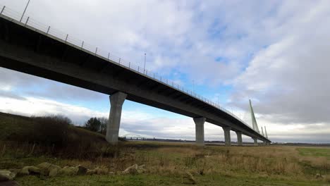 Speeding-time-lapse-clouds-passing-over-rural-countryside-marshland-suspension-bridge