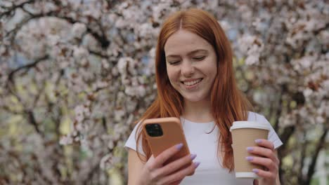 woman with coffee and phone in a spring park