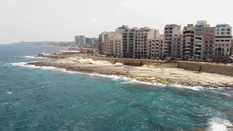 panorámica, imágenes aéreas de drones de 4k, volando rápidamente sobre el mar mediterráneo, revelando la costa de la ciudad isleña densamente poblada de sliema, malta