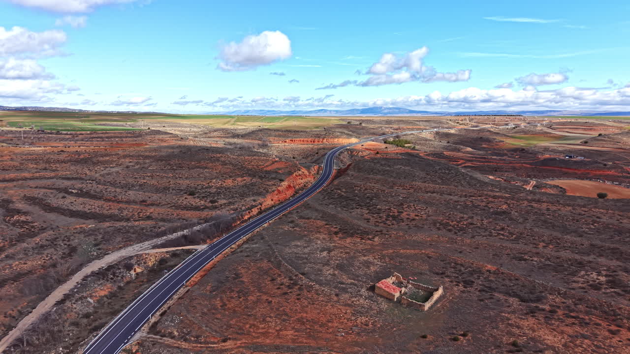 Strada che si snoda attraverso un paesaggio arido con vegetazione rada in una zona remota di giorno sotto un cielo sereno