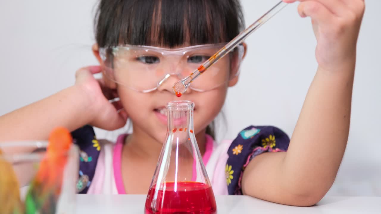 Lapset oppivat ja tekevät tiedekokeita luokkahuoneessa. Pieni tyttö leikkii tiedekokeilla kotiopetuksessa. Helppoja ja hauskoja tiedekokeita lapsille kotona.