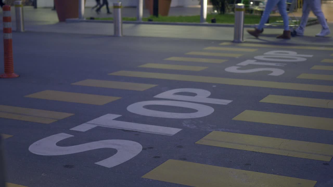 사람들이 밤에 교차로를 가로질러 걸어가며 멈추는 표지판을 가지고 있습니다.