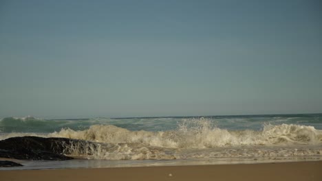 close up slow motion of waves breaking on the beach against rocks