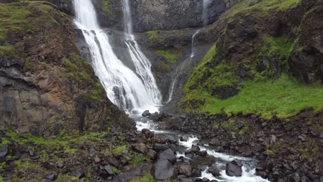 Glymur-waterfall-falling-down-rocky-mossy-cliff-in-Iceland,-aerial-drone-view