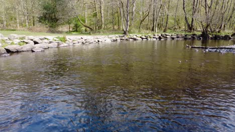 Eine-Laufende-Aufnahme-Der-Sonne,-Die-Sich-Im-Fluss-Rothay-Außerhalb-Des-Dorfes-Widerspiegelt