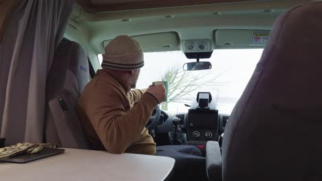 drinking coffee or tea in campervan, older man closeup view, having a break after long journey