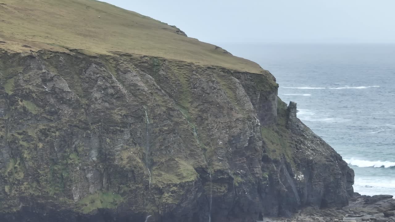 disparo de drones de cerca de altos acantilados con cascadas y aves en la isla de achill