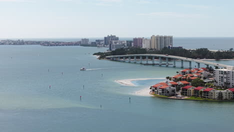 drone following a boat in front of the sand key bridge, in sunny clearwater, usa