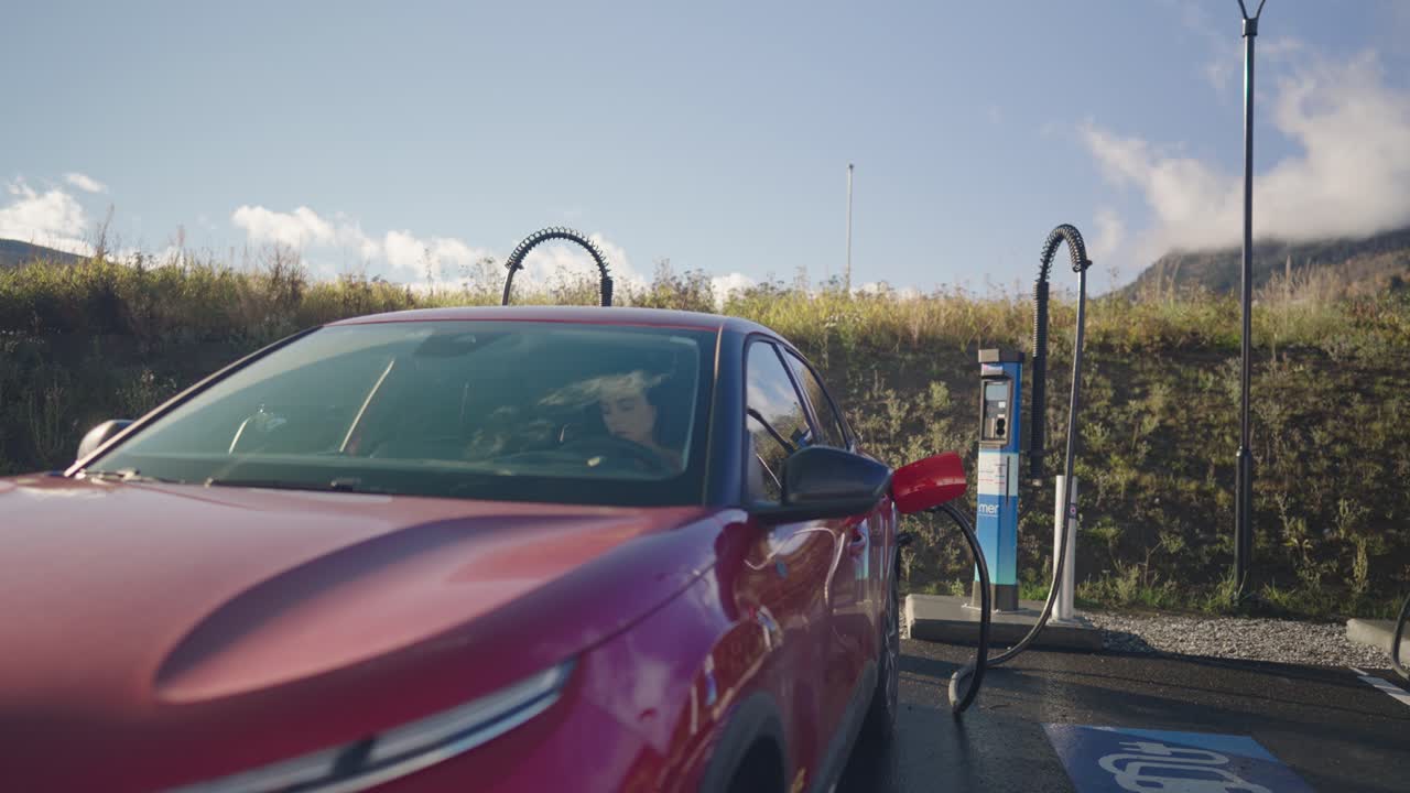 Elektrikli aracını şarj ederken arabasında oturan kadın.