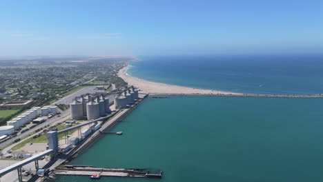 puerto de necochea silos, playa y océano bajo un cielo azul claro, vista aérea